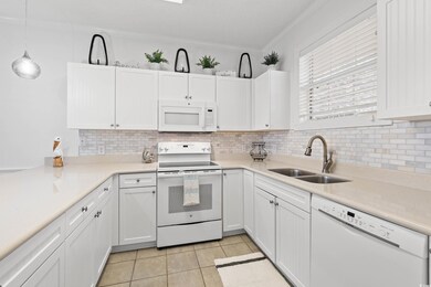 Kitchen featuring white appliances, ornamental molding, white cabinets, decorative light fixtures, and tasteful backsplash
