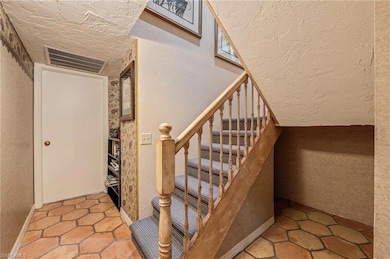 Stairway featuring a textured ceiling and tile pat