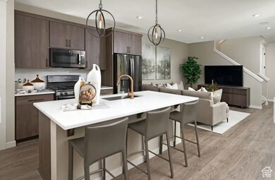 Kitchen featuring a breakfast bar area, light wood-style flooring, appliances with stainless steel finishes, decorative light fixtures, and recessed lighting