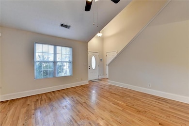 Foyer with light wood finished floors, a ceiling fan, high vaulted ceiling, and stairs