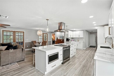 Kitchen featuring light stone counters, stainless steel appliances, recessed lighting, open floor plan, and white cabinets