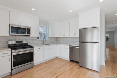 Kitchen featuring stainless steel appliances, white cabinetry, recessed lighting, light wood finished floors, and light stone countertops