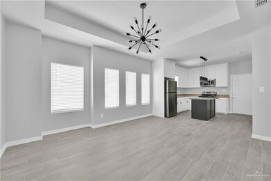 Kitchen with appliances with stainless steel finishes, a tray ceiling, open floor plan, a chandelier, and a center island