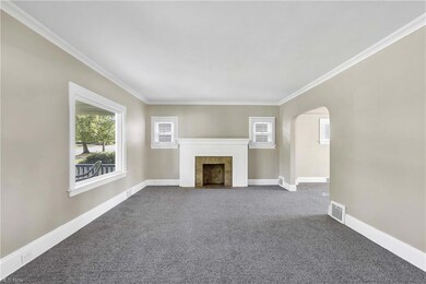 Freshly painted and carpeted living room with ornamental ceiling moldings, fire place with gas line.