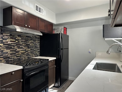 Kitchen featuring black appliances, range hood, ba