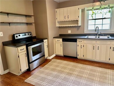 Kitchen with dishwashing machine, electric stove, a sink, and open shelves
