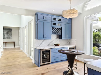Indoor dry bar featuring wine cooler, light wood-t