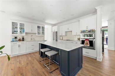 Kitchen with appliances with stainless steel finishes, tasteful backsplash, white cabinets, a breakfast bar, and crown molding