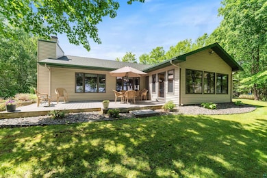 Rear view of house with a chimney, a deck, and a lawn