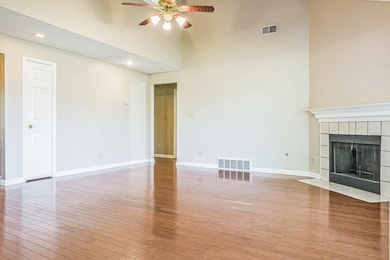 Unfurnished living room with ceiling fan, a towering ceiling, light wood finished floors, baseboards, and a tile fireplace