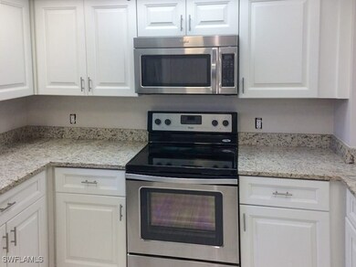 Kitchen featuring white cabinets, light stone coun