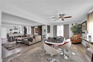 Living area with a barn door, a ceiling fan, and l