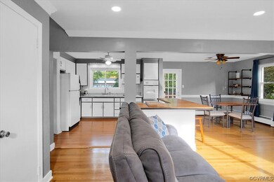 Living room with a wealth of natural light, ornamental molding, light hardwood floors and ceiling fan