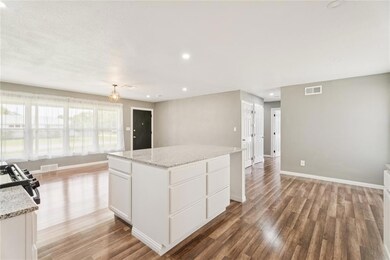 Kitchen featuring range, light wood finished floors, white cabinets, recessed lighting, and a kitchen island