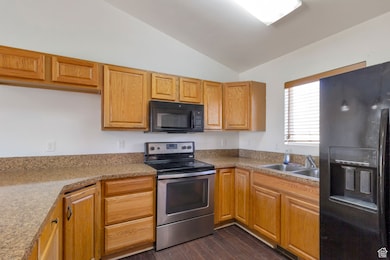 Kitchen featuring black appliances, lofted ceiling, and dark wood-style flooring