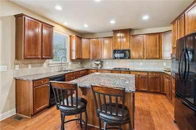 Spacious kitchen featuring rich wood cabinetry, granite countertops, and large center island — perfect for cooking and entertaining!