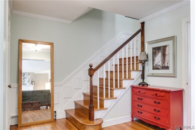 The foyer is inviting with hardwood flooring, crown and wall molding, and a coat closet.