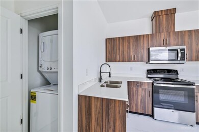 Kitchen with stacked washer and clothes dryer, appliances with stainless steel finishes, modern cabinets, and light countertops