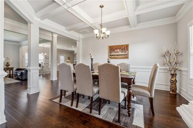 Dining space featuring a chandelier, healthy amount of natural light, dark wood finished floors, beam ceiling, and coffered ceiling