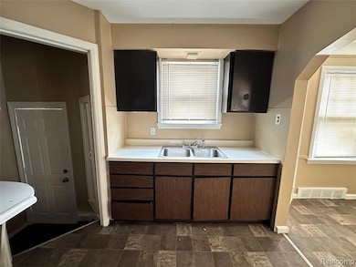 Kitchen with light countertops, stone finish floors, and dark cabinets