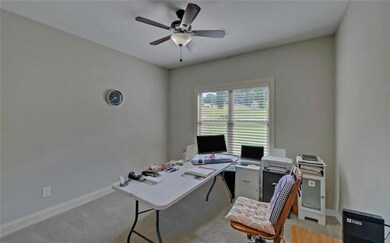 Office area with ceiling fan and light colored carpet