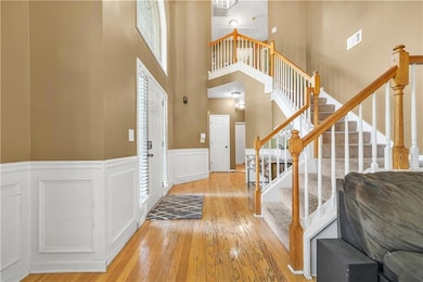 Entrance foyer featuring a wainscoted wall, a decorative wall, wood-type flooring, stairs, and a towering ceiling