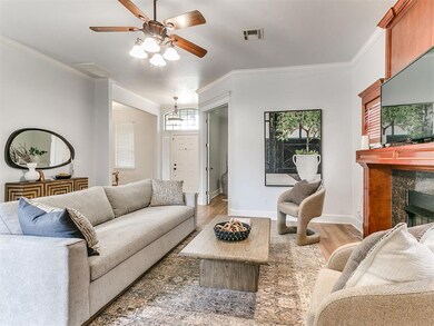 Living room featuring crown molding, light wood-style flooring, a ceiling fan, and a high end fireplace