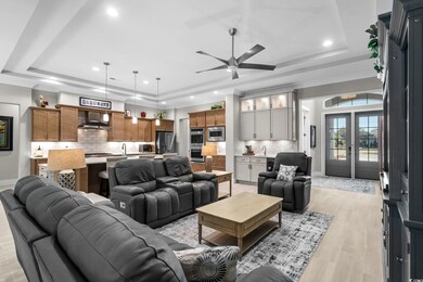Living area featuring a tray ceiling, a ceiling fan, recessed lighting, french doors, and light wood-type flooring
