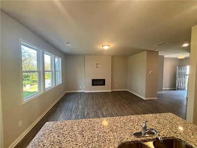 Unfurnished living room with dark wood-type flooring and a glass covered fireplace