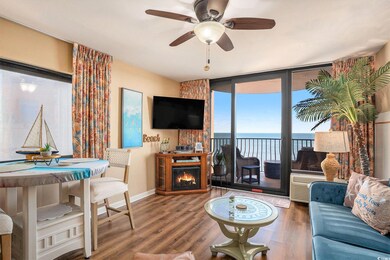 Living room with wood finished floors, plenty of natural light, a wall of windows, a warm lit fireplace, and ceiling fan