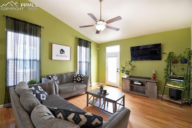 Living area featuring vaulted ceiling, baseboards, ceiling fan, and light wood-style flooring