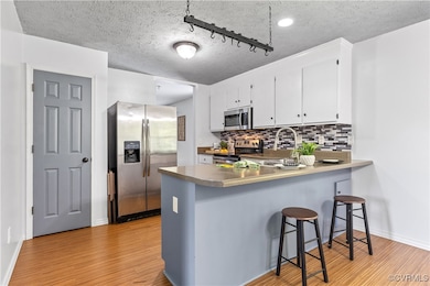 Kitchen featuring white cabinets, sink, a textured