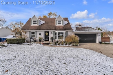 Cape cod house featuring brick siding, driveway, a garage, and roof with shingles