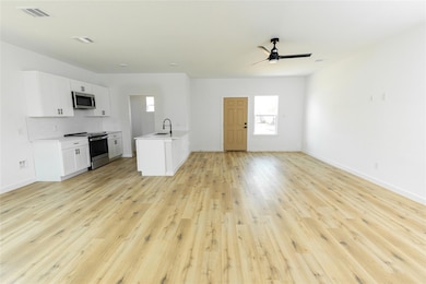 Unfurnished living room featuring sink, light hard