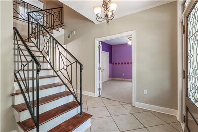 Foyer boasts wood stairway, iron railing and tile