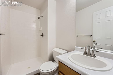 Full bathroom featuring toilet, vanity, and tiled shower