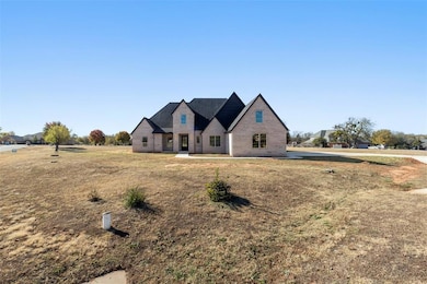 French country inspired facade featuring a front lawn and brick siding