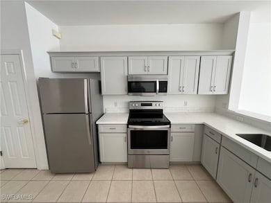 Kitchen featuring gray cabinets, light tile patterned floors, and stainless steel appliances