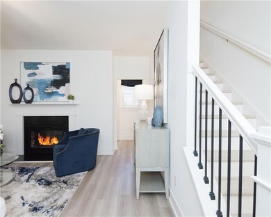Living room with stairway, wood finished floors, and a glass covered fireplace