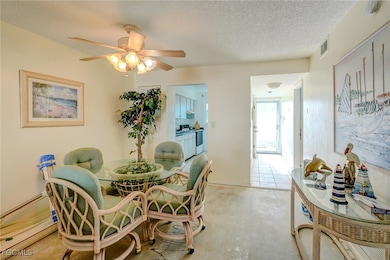 Dining area with a textured ceiling, concrete floors, and a ceiling fan