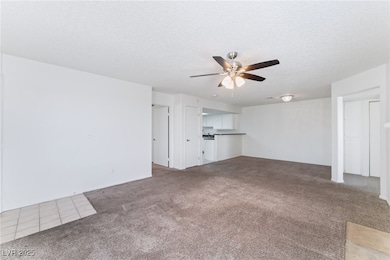 Unfurnished living room with carpet flooring, a textured ceiling, and a ceiling fan