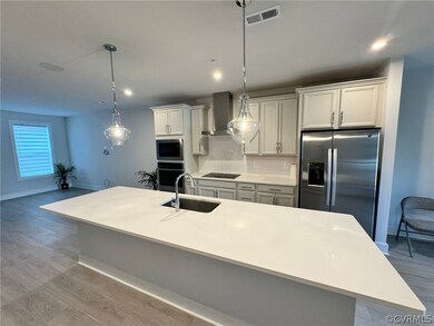Kitchen featuring appliances with stainless steel finishes, light wood-type flooring, tasteful backsplash, sink, and wall chimney exhaust hood