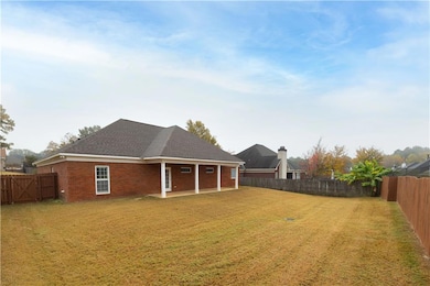 Back of house featuring a fenced backyard, a shingled roof, brick siding, and a patio area