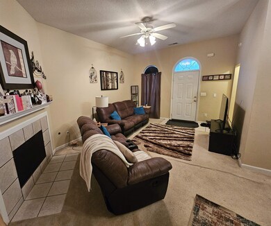 Living room with ceiling fan, light colored carpet