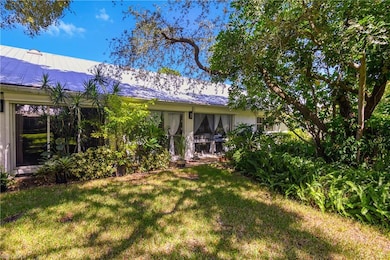 Rear view of house featuring a lawn and a metal roof