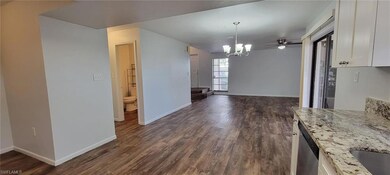 Unfurnished dining area featuring a chandelier, dark wood-type flooring, and baseboards