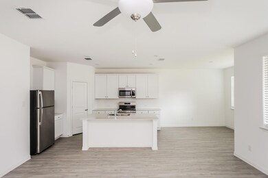 Kitchen featuring appliances with stainless steel finishes, light hardwood / wood-style flooring, an island with sink, and white cabinets
