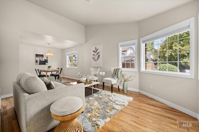 Living area with lofted ceiling, light wood-type flooring, and a chandelier