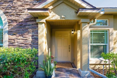 Doorway to property featuring stucco siding and stone siding