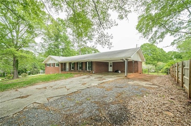 Ranch-style house with brick siding, driveway, and a carport